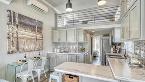 Een moderne keuken met een centraal eiland, boven- en onderkasten, en een zithoek met stoelen en een tafel.