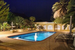 Een buitenzwembad, parasols bij het zwembad en ligstoelen