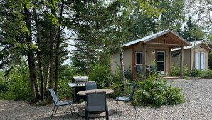 A rustic cabin with a gravel driveway, surrounded by trees. - Cabin #4 centrally located to beaches, golfing and the Confederation Trail! (Mount Stewart)