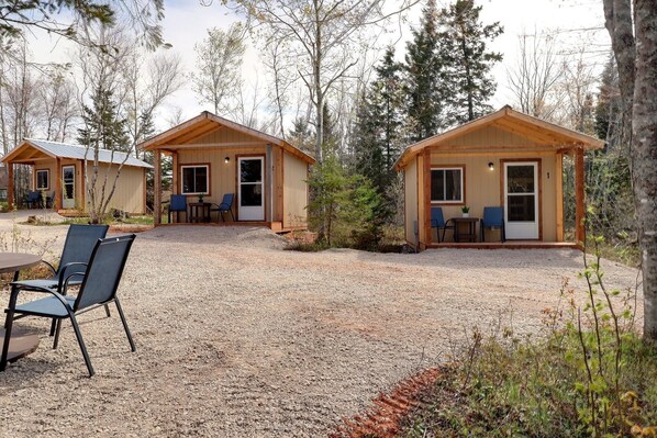 A cabin with a gravel driveway, a table with chairs, and a small garden area.