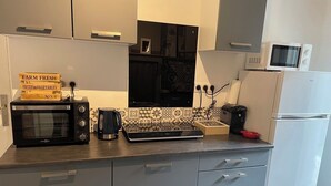 A compact kitchen with a microwave, toaster, kettle, and a coffee maker. There are cabinets with handles and a refrigerator. - 1 Bedroom Apartment in BÃ©ziers (Béziers)