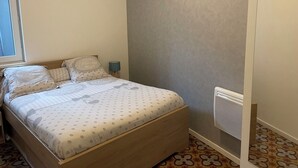 A bedroom with a bed, pillows, a bedside lamp, and a radiator. - 1 Bedroom Apartment in BÃ©ziers (Béziers)