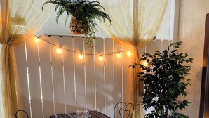 A cozy corner with a table and chairs, a potted plant, and string lights. - Woodside Retreat in the Heart of Amish Country (Nappanee)