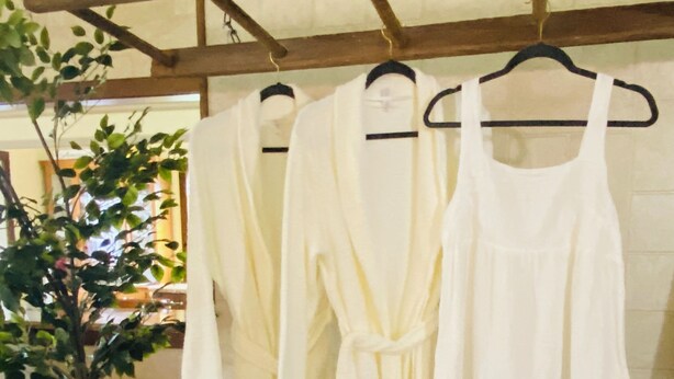 A rack of white robes hanging on a wall, a potted plant, and a wooden beam structure. - Woodside Retreat in the Heart of Amish Country (Nappanee)