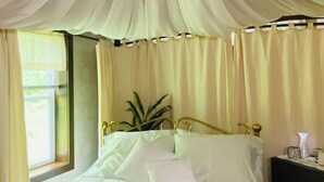A bed with white linens, a gold headboard, and a bedside table with a clock. - Woodside Retreat in the Heart of Amish Country (Nappanee)