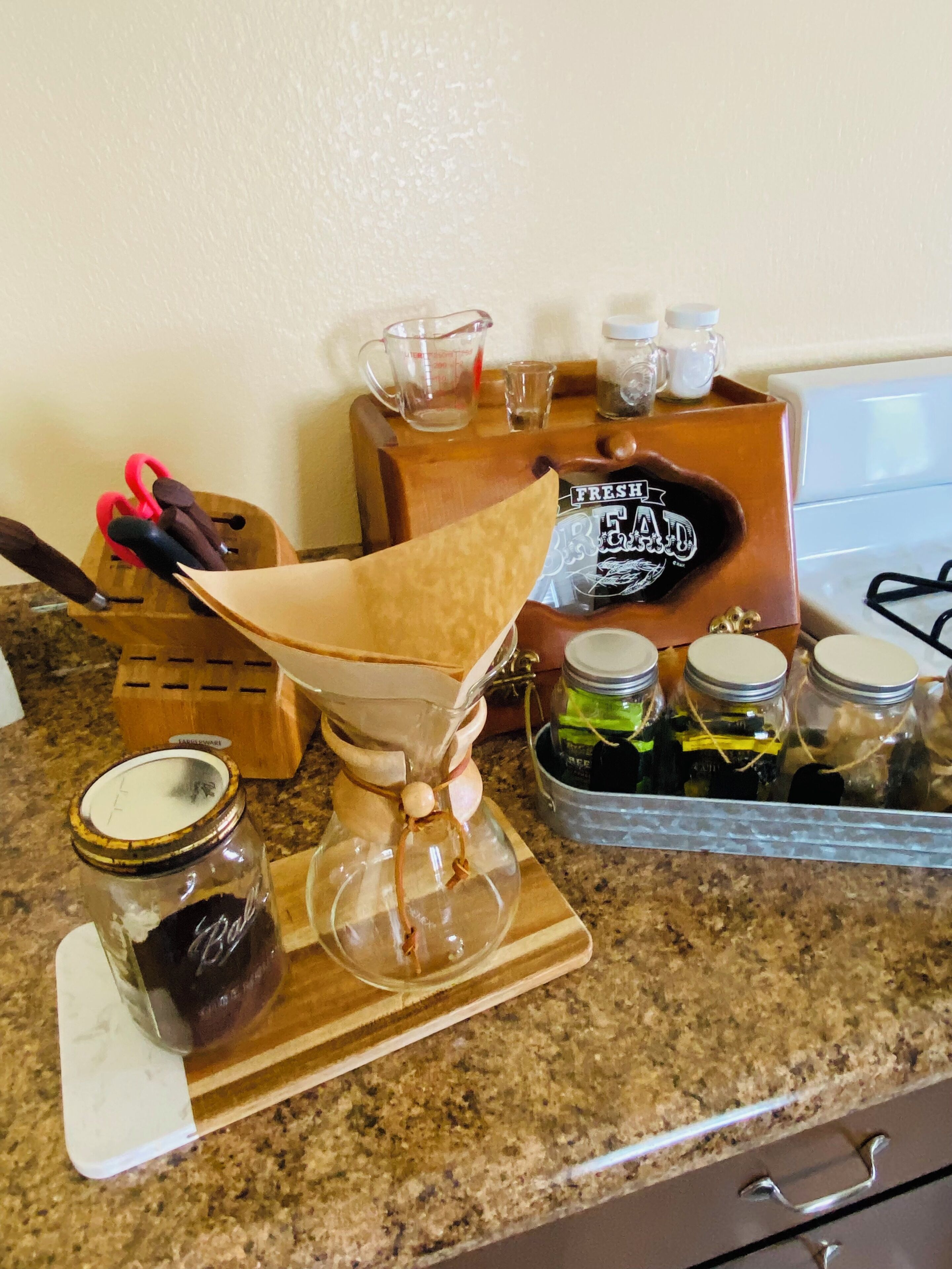 Un plan de travail de cuisine avec une cafetière à piston, des bocaux et des ustensiles de cuisine.