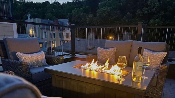 Une terrasse sur le toit dotée d’un foyer, d’un espace salon et de verres à vin.