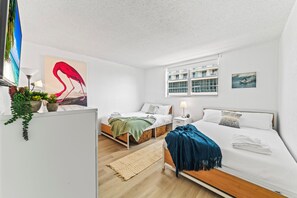 Une chambre d’hôtel moderne avec deux lits, une grande fenêtre et une vue sur l’immeuble.