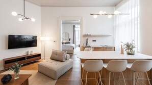 A modern living room with a TV, sofa, and dining area with chairs.