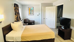 Ein Hotelzimmer mit Bett, Sessel, Fernseher und Tür.