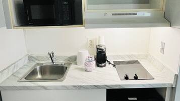 A compact kitchen with a built-in microwave, a coffee maker, and a dishwasher.