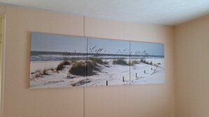 Una pared con un cuadro grande de una escena de playa.