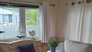 Una sala de estar acogedora con un sofá, una mesita con una planta y una ventana con cortinas.
