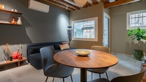 Un salon moderne avec une table ronde en bois, des chaises noires, un canapé bleu foncé et une grande fenêtre.