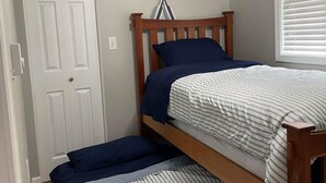 A bedroom with two bunk beds, a ceiling fan, a door, and a window with blinds. - Cozy Lakefront Cottage (Colon)