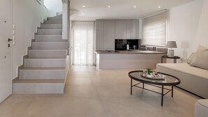 A modern living space with a staircase, a kitchen area, and a seating area with a coffee table.