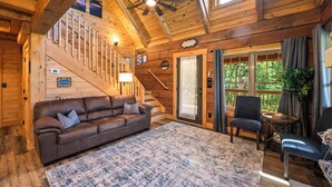 Ein Holzinterieur mit einem braunen Ledersofa, einem blauen Teppich mit Muster und einem Deckenventilator.