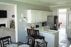 A kitchen with white cabinets, a central island, a sink, and a refrigerator. - Walking distance to Coler MTN Bike - 3BR 2BA (Bentonville)