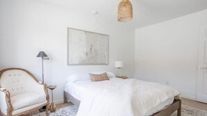 Un dormitorio con una cama, una silla, una lámpara y una lámpara colgante.