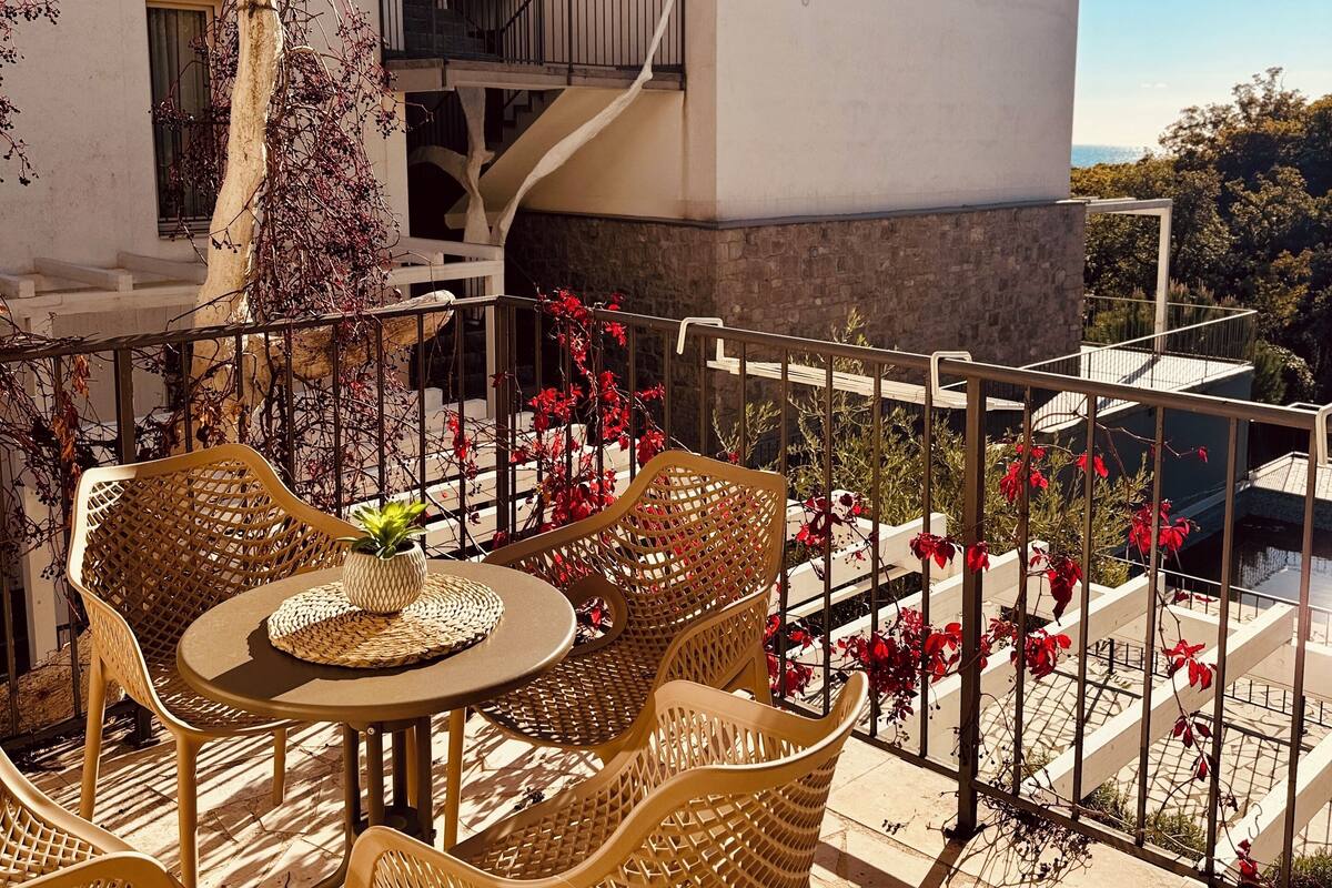 A terrace with wicker furniture and a view of a white building with a balcony.