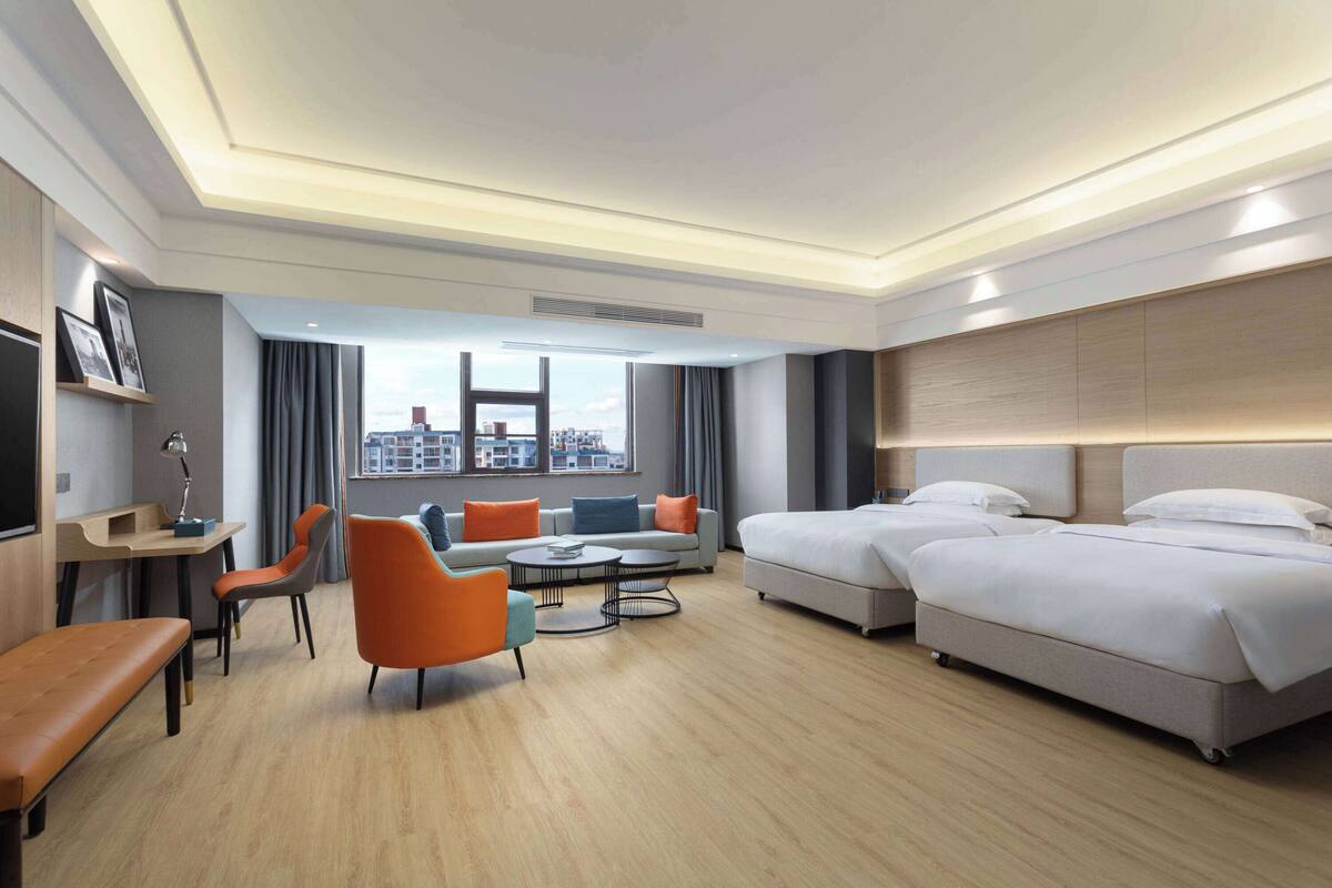 Una habitación de hotel moderna con una cama grande, un sofá, un escritorio y vistas a la ciudad.