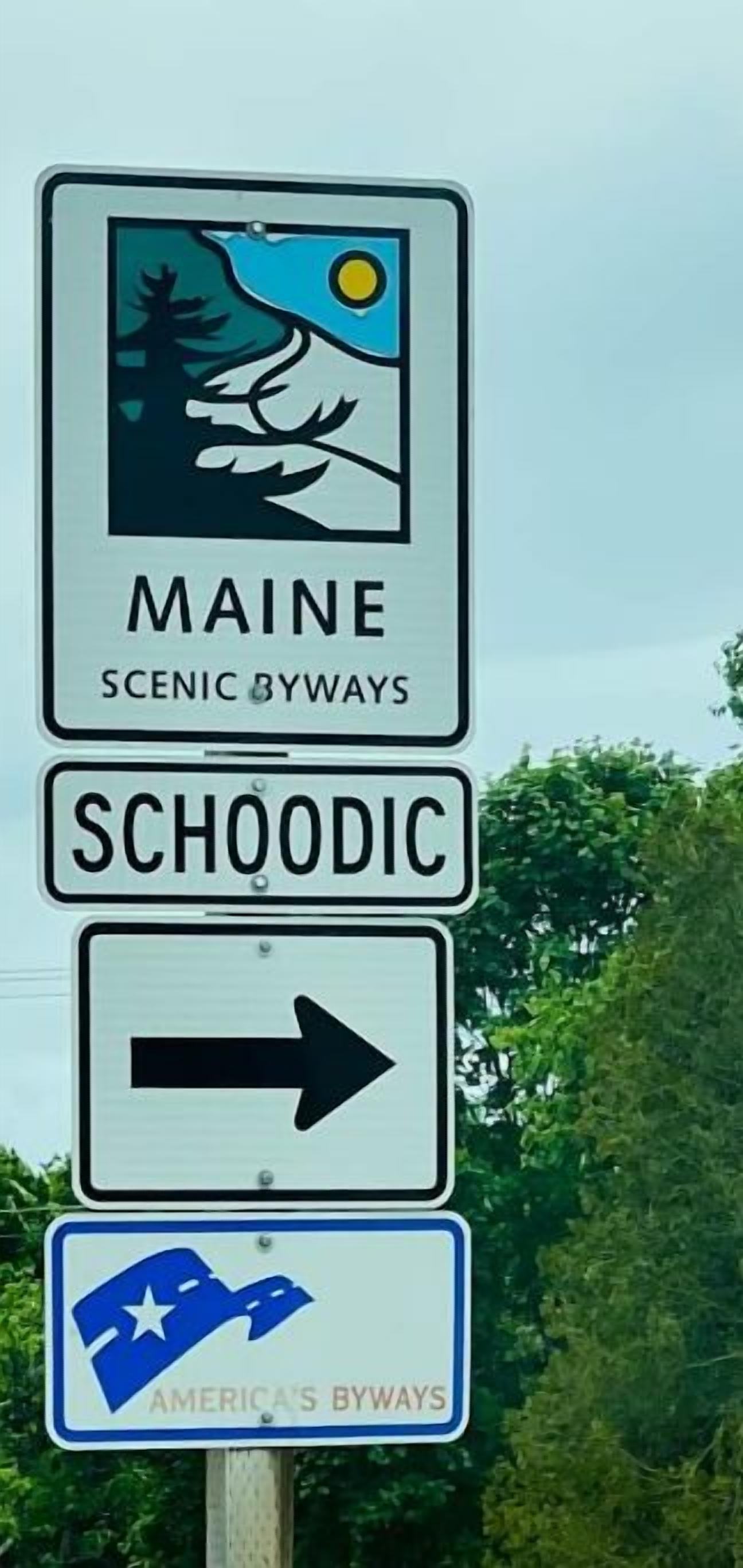 A sign indicating Maine Scenic Byways and Schooldric with an arrow pointing right.