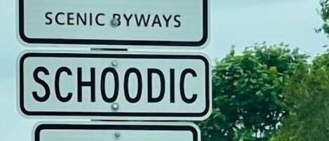 A sign indicating Maine Scenic Byways and Schooldric with an arrow pointing right.