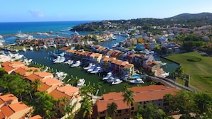 A marina with boats docked, surrounded by colorful buildings and palm trees. - Park Royal Club Cala Stylish 2BR Condo (Humacao)