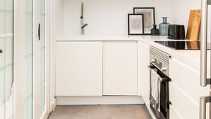 A modern kitchen with white cabinetry, a stainless steel refrigerator, and a built-in oven.