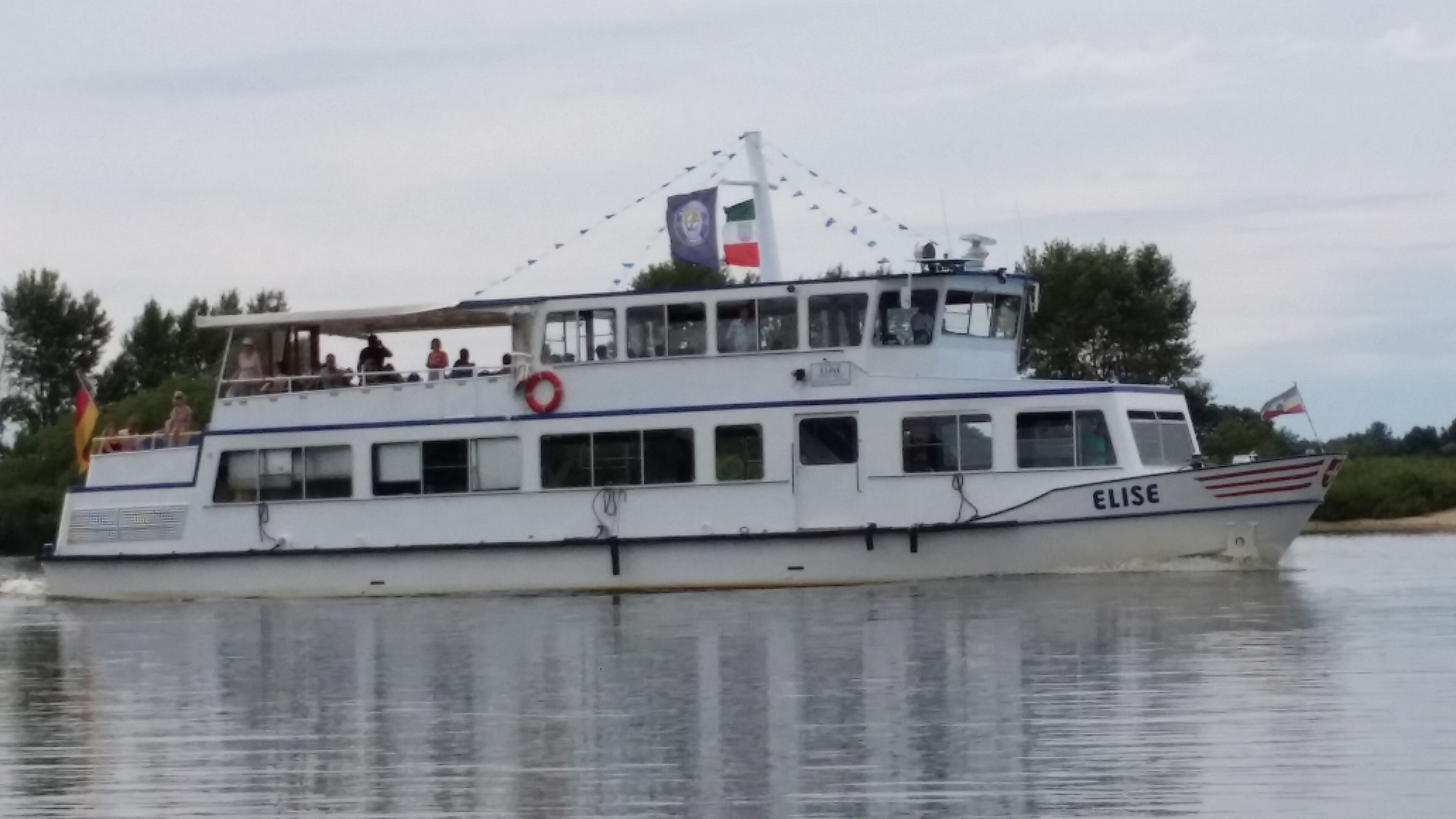 A boat with the name 'ELISE' on its side, a lifebuoy, and flags.