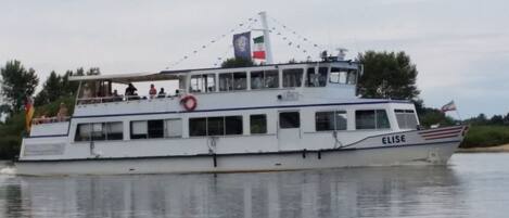 A boat with the name 'ELISE' on its side, a lifebuoy, and flags.