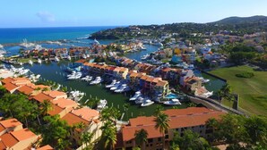 A marina with boats docked, surrounded by colorful buildings and palm trees.