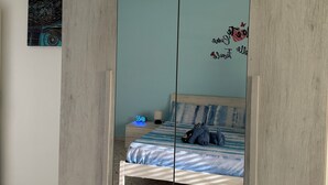 Une chambre à coucher comprenant un lit, une table de chevet, une horloge murale et une armoire avec un miroir.