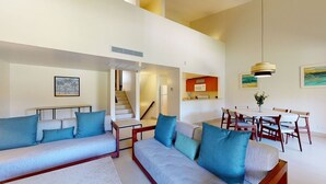 A spacious living area with a sofa set, a dining table with chairs, and a staircase leading to an upper level. - Comfortable 3BR Condo at Park Royal Club Cala w Outdoor Pool (Humacao)
