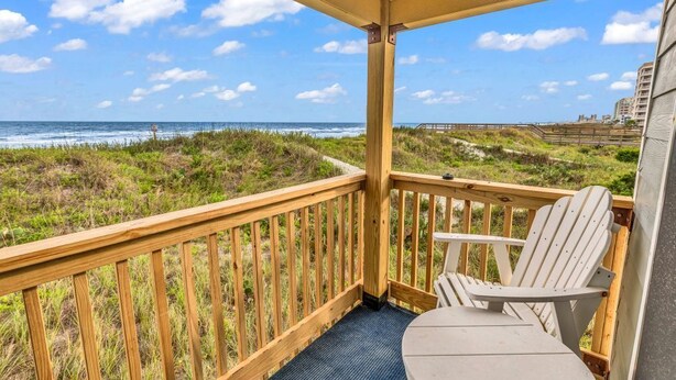 Eine Holzterrasse mit Blick auf Strand und Meer.
