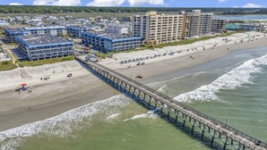 Ein Küstenhotel mit mehreren Gebäuden, einem Strand und einem Steg.