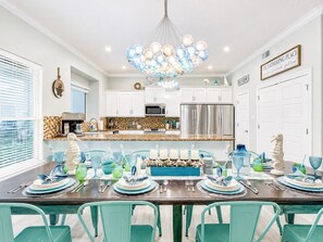 A modern kitchen with white cabinets, stainless steel appliances, and a dining area set for a meal.