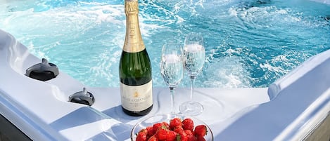 Een bubbelbad met een fles Moët & Chandon champagne, twee glazen en een schaal aardbeien.