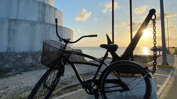 Una bicicleta estacionada cerca de un letrero que dice "ISLA COZUMEL", con un atardecer de fondo.