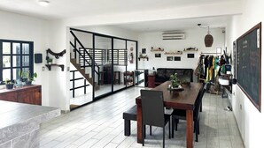 A spacious living area with a dining table, chairs, a sofa, and a staircase leading to another room. - La Perle Noire (Cozumel)