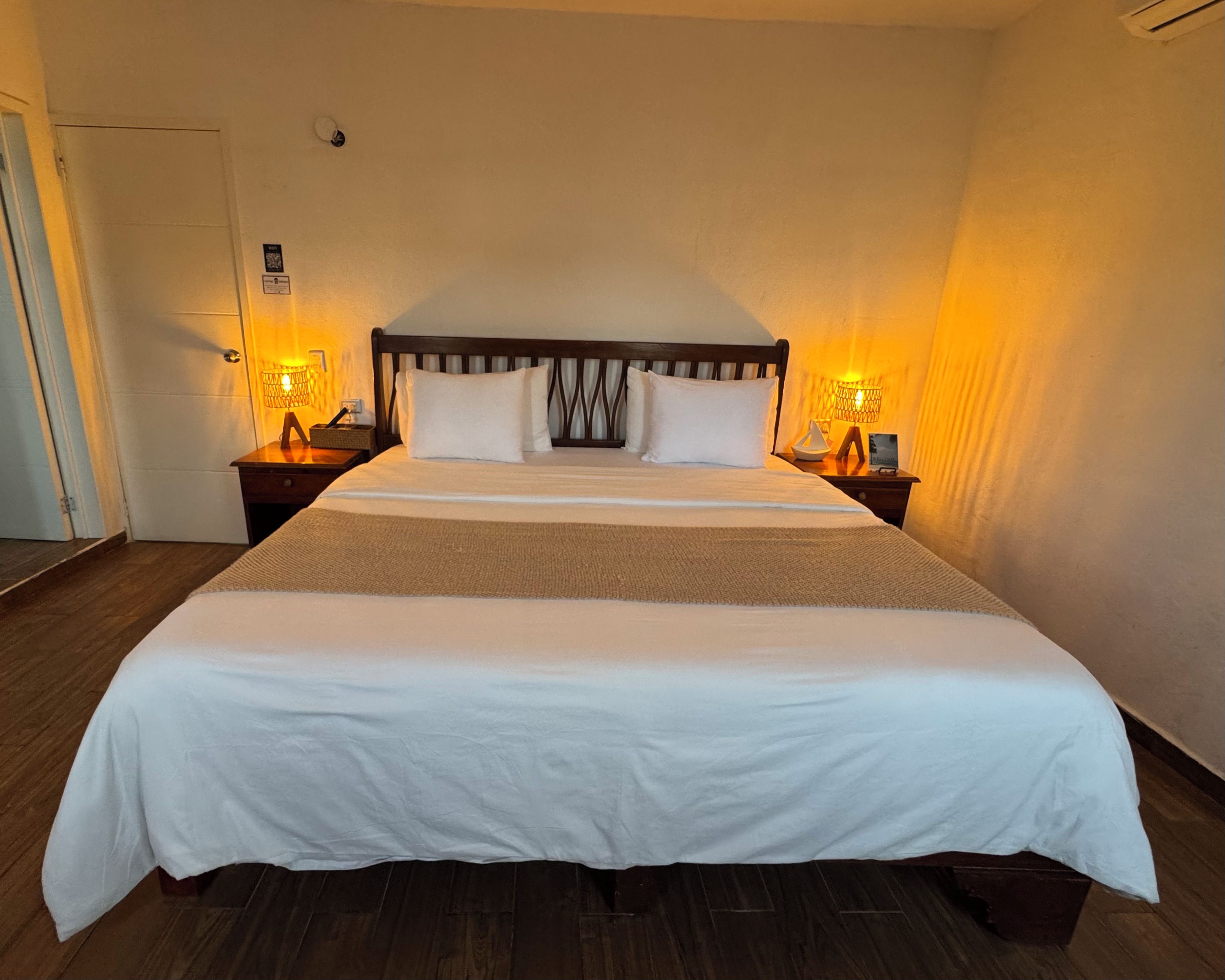 A hotel room with a large bed, two bedside tables, and a door.