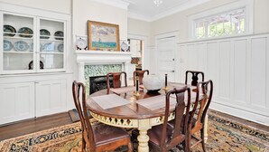 A dining room with a round table, wooden chairs, a chandelier, a fireplace, and a view of the outdoors through a window. - Going to Carolina! Historic Downtown Wilmington (Wilmington)