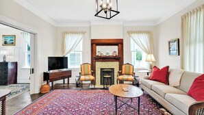 A living room with a fireplace, a sofa, a television, and a patterned rug. - Going to Carolina! Historic Downtown Wilmington (Wilmington)