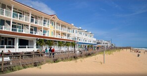 A beachfront hotel with multiple balconies, a boardwalk, and a sandy beach. - Blissfully beachy!  Bright & Cozy!  Walk/Trolley/Drive to the Beach in Minutes! (Bethany Beach)