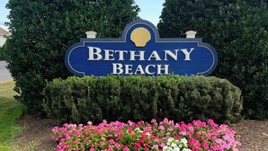 Bethany Beach -nimikyltti, jossa on koristeellinen simpukankuorikuva ja sen edessä kukkapenkki.