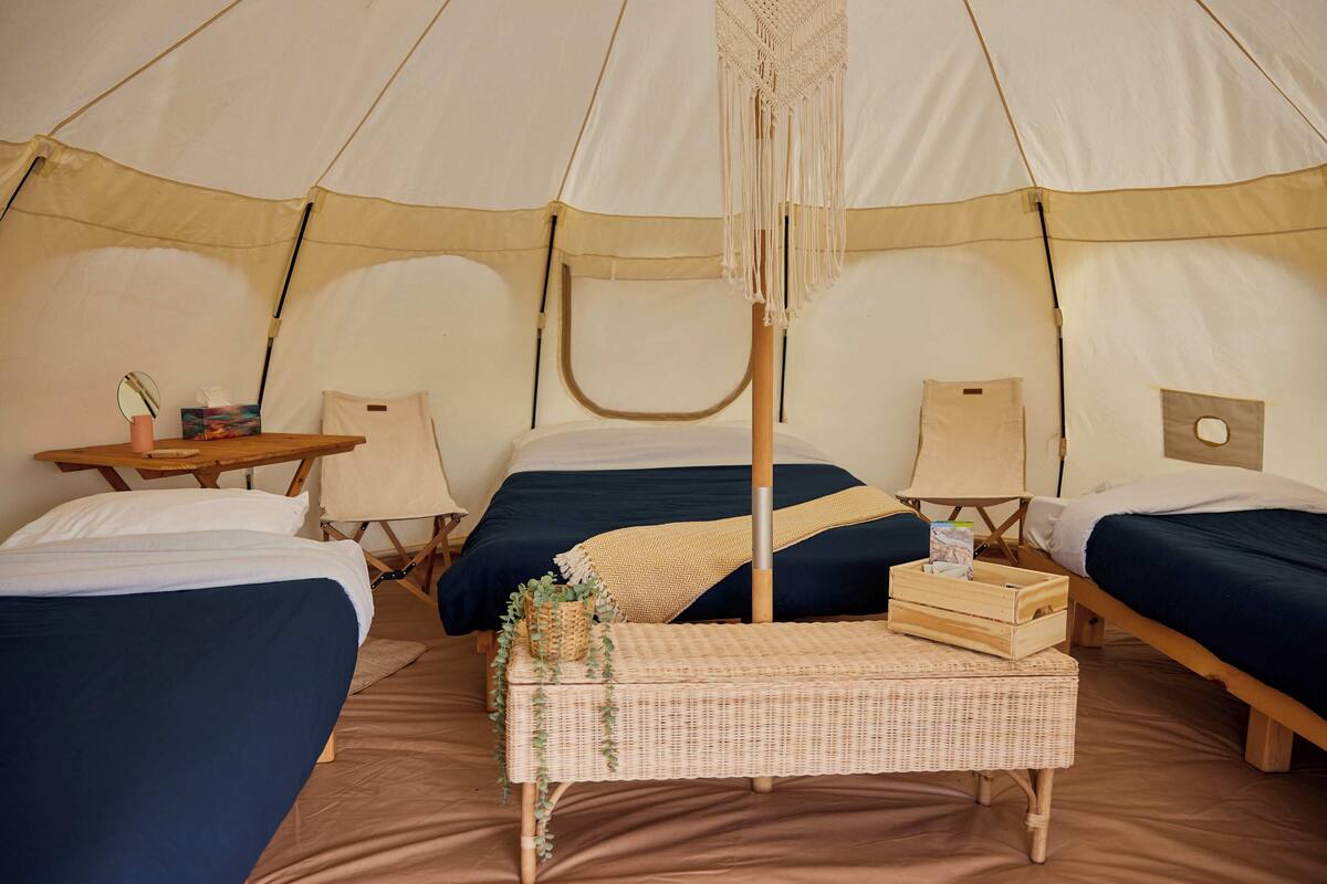 A tent with two beds, a small table, and a bench.