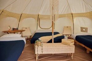 A tent with two beds, a small table, and a bench. - Hôtel UNIQ - Forêt Ô Cascades - Tentes Glamping (Rawdon)