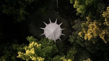 Vista aérea de un bosque con una estructura blanca en forma de paraguas en el centro.