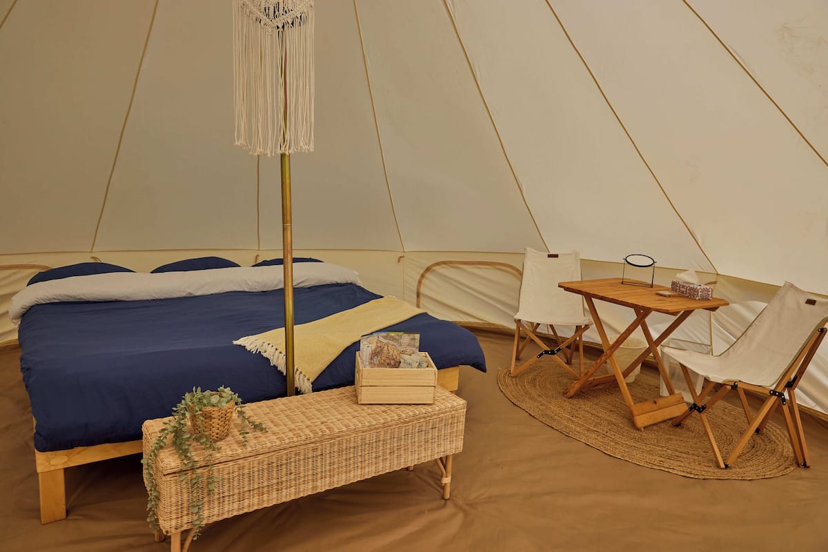 A tent with a bed, a table, and a chair.