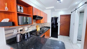 A modern kitchen with wooden cabinets, a microwave, a stove, and a sink.